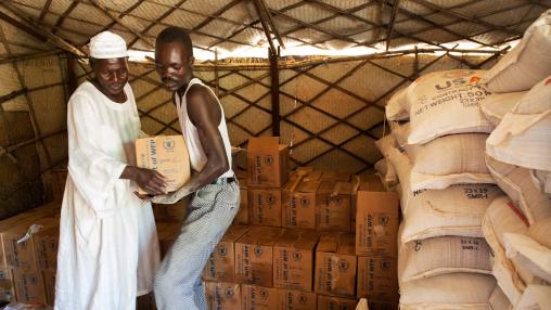 Two men in Darfur carry boxes of food aid, including wheat. Supply disruptions and rising prices of wheat and other items are causing problems for countries in the Middle East and elsewhere as the Russia-Ukraine war continues.